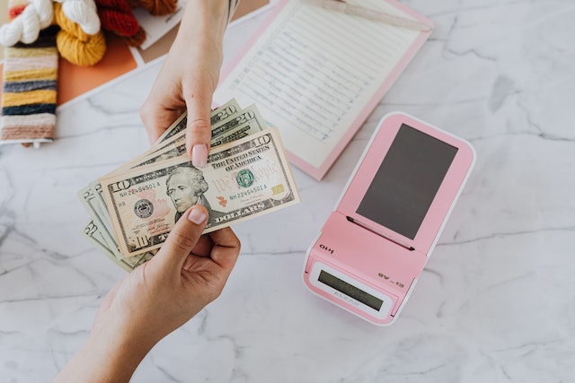 Two hands exchanging U.S. dollars over a table